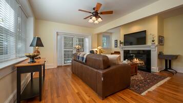 A living room with a fireplace, a ceiling fan, and a television.