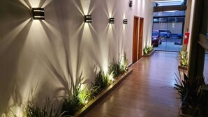 Un couloir doté d’un éclairage encastré, d’un plancher en bois et d’un mur bordé de plantes.