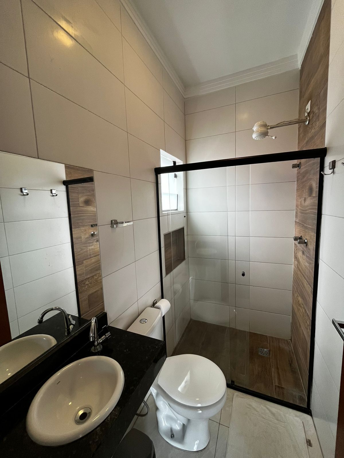 Un baño moderno con un espejo grande, un lavabo, un inodoro y una zona de ducha.