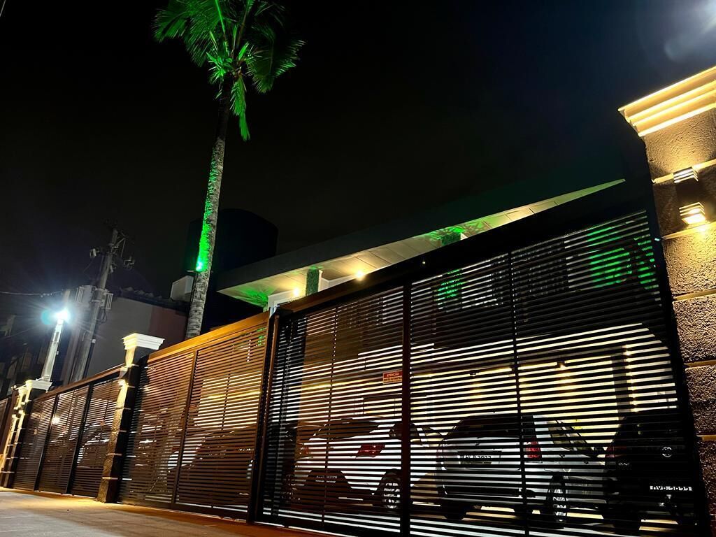 A gated entrance with a palm tree and a building with a sloped roof.