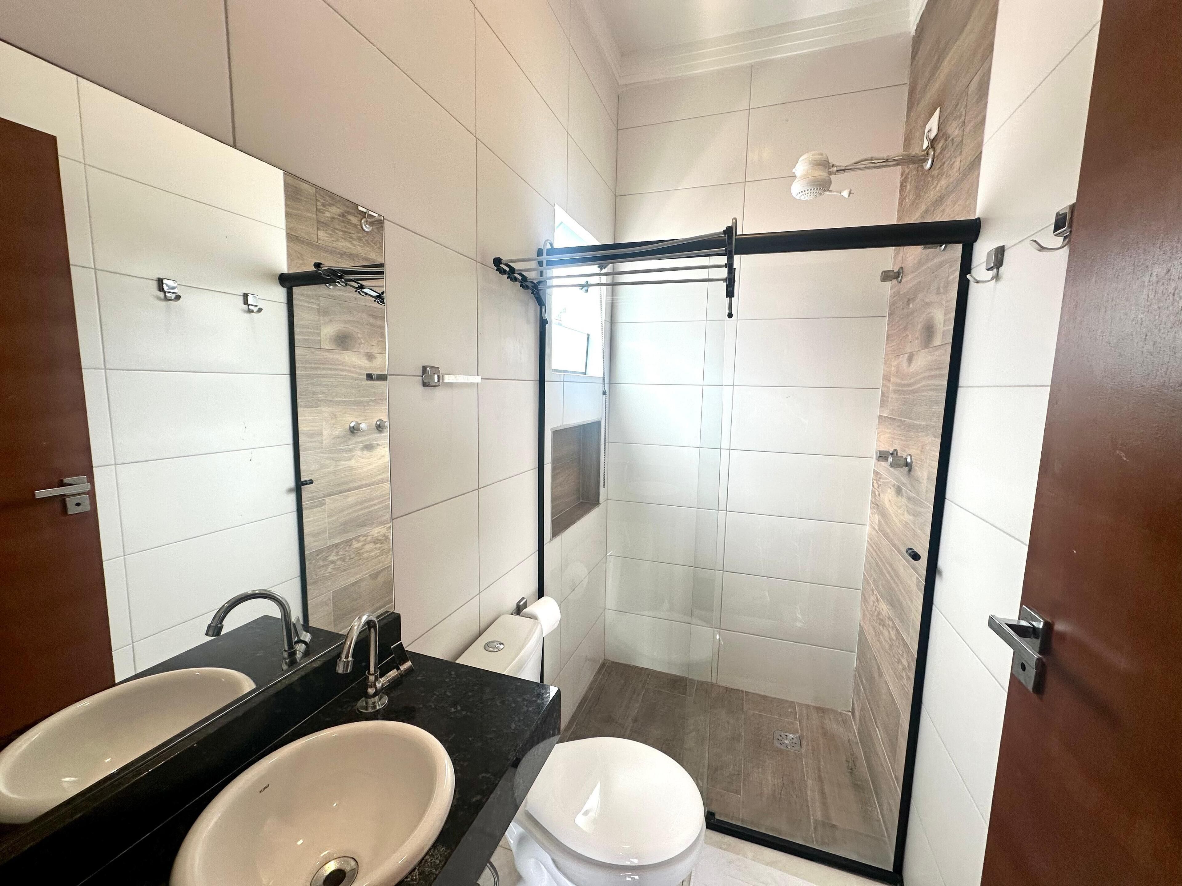 Un baño moderno con cabina de ducha de vidrio, tocador doble y un inodoro.