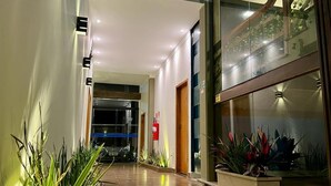 Un couloir d’hôtel avec un extincteur, une alarme incendie et des plantes en pot.