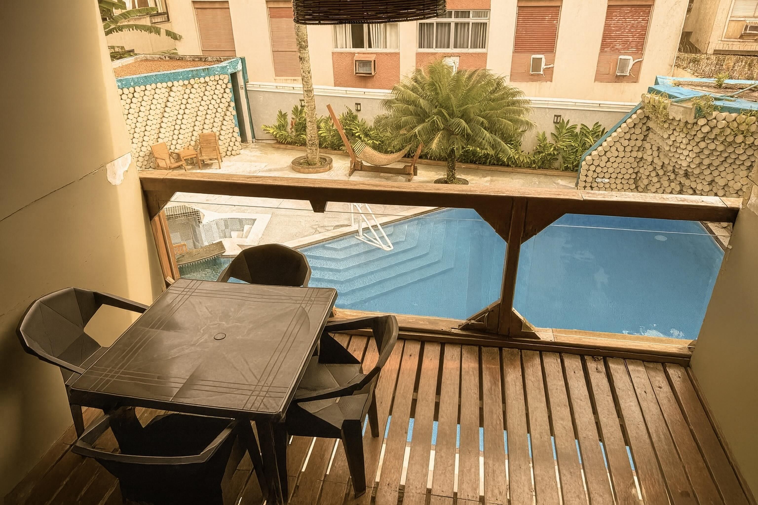 Un balcón con piscina, piso de madera y una mesa con sillas.