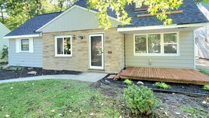 A two-story house with a stone facade, a front porch, and a well-maintained lawn. - 2 KING 3 QUEEN BEDS. Spacious. Quiet Neighborhood (Euclid)