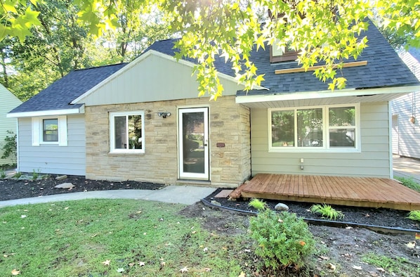 A two-story house with a stone facade, a front porch, and a well-maintained lawn. - 2 KING 3 QUEEN BEDS. Spacious. Quiet Neighborhood (Euclid)