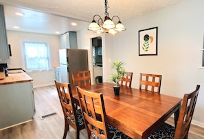 A dining area with a wooden table, six chairs, a chandelier, a potted plant, and a framed artwork on the wall. - 2 KING 3 QUEEN BEDS. Spacious. Quiet Neighborhood (Euclid)