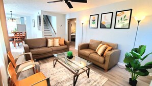 A living room with two sofas, a glass coffee table, and a dining area with chairs and a table. - 2 KING 3 QUEEN BEDS. Spacious. Quiet Neighborhood (Euclid)