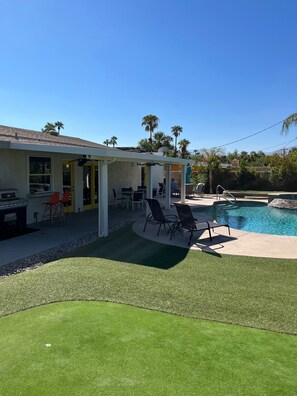 A backyard with a swimming pool, outdoor seating, and a barbecue area.