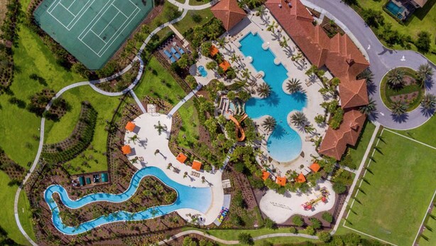 Vista aérea de un complejo turístico con varias piscinas, una cancha de tenis y diversas zonas de estar al aire libre.