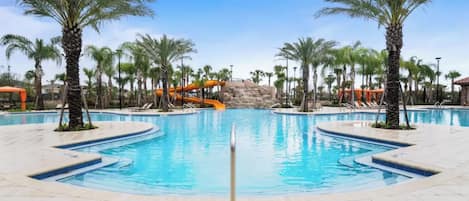 A swimming pool with multiple lanes, surrounded by palm trees and a water slide.