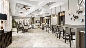 Una cocina moderna con piso de mármol, una barra con taburetes y un comedor con sillas.