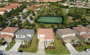 Houses with red-tiled roofs surround a tennis court.