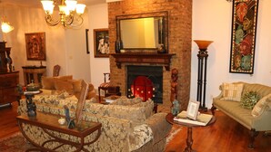 Ein traditionell eingerichtetes Wohnzimmer mit Kamin, gemusterten Sofas, einem Couchtisch und einem großen Spiegel über dem Kamin.