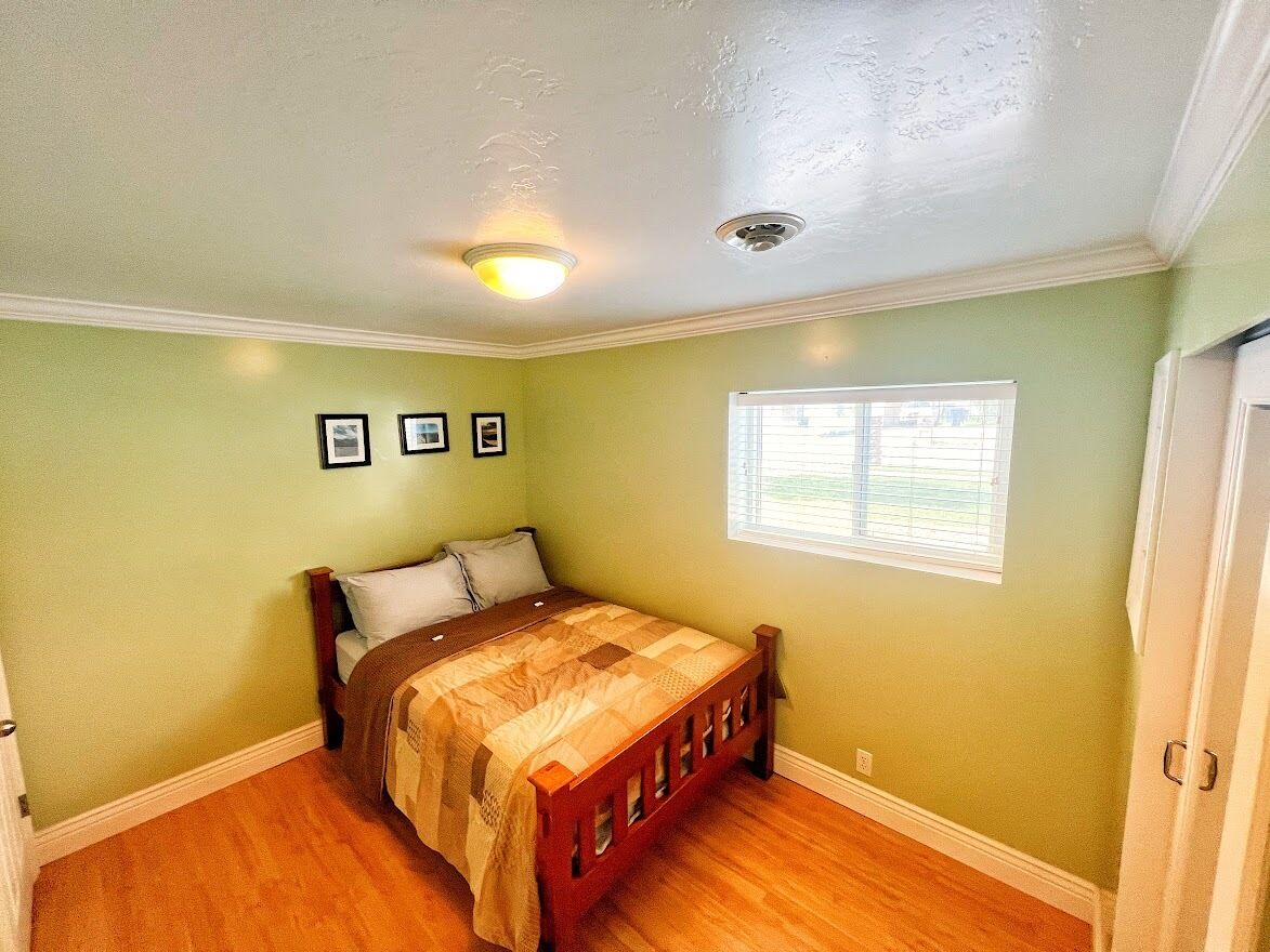A bedroom with a bed, a window, and a ceiling light.