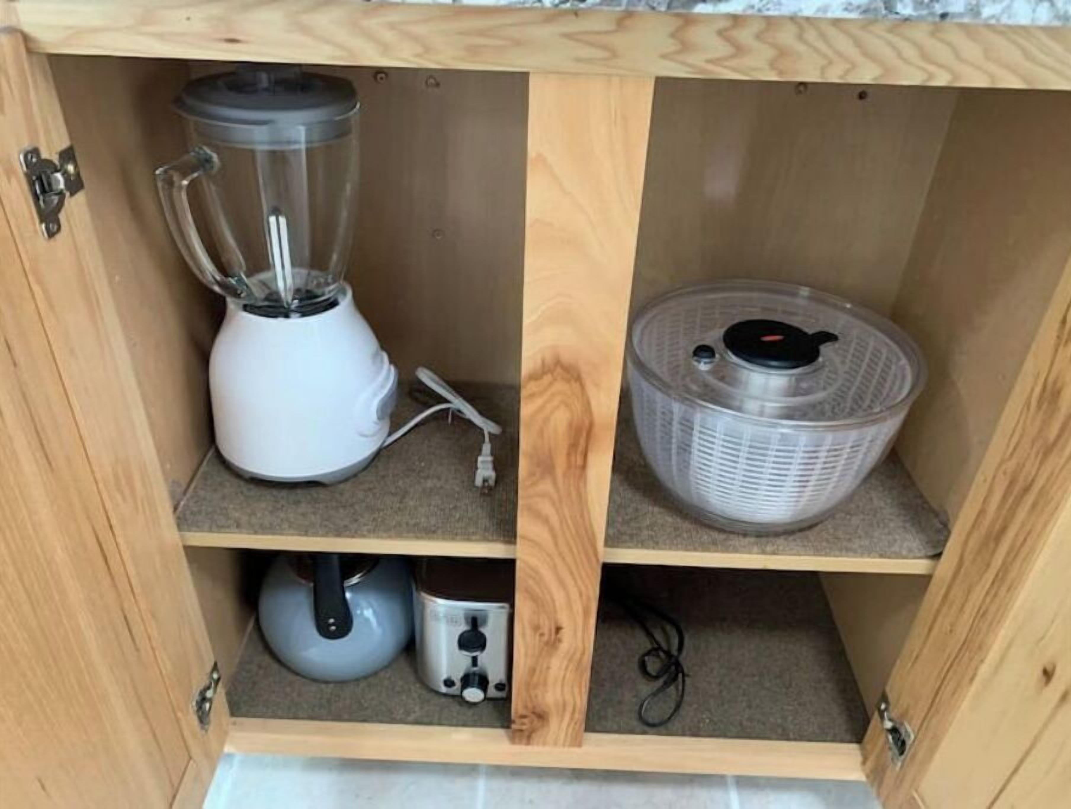 Un mueble de madera con una licuadora, una tetera y un recipiente sobre estantes.