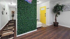A hallway with a green wall, a yellow door, and a potted plant.