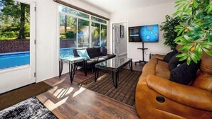 A spacious living room with a pool view, a ceiling fan, and a flat-screen TV.
