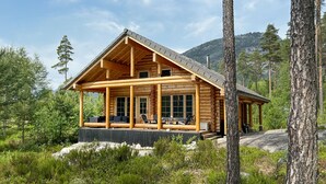 Eine Blockhütte mit Veranda, großen Fenstern und Bergblick.