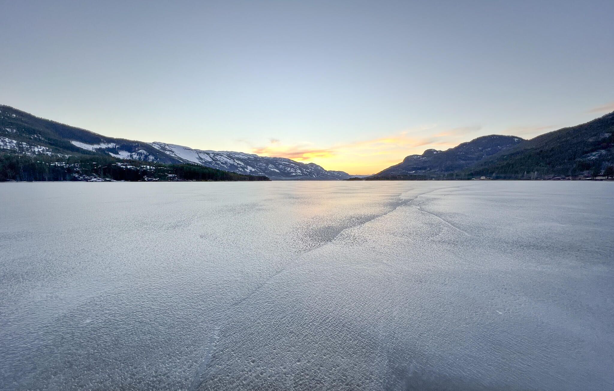 A frozen lake with mountains in the background.