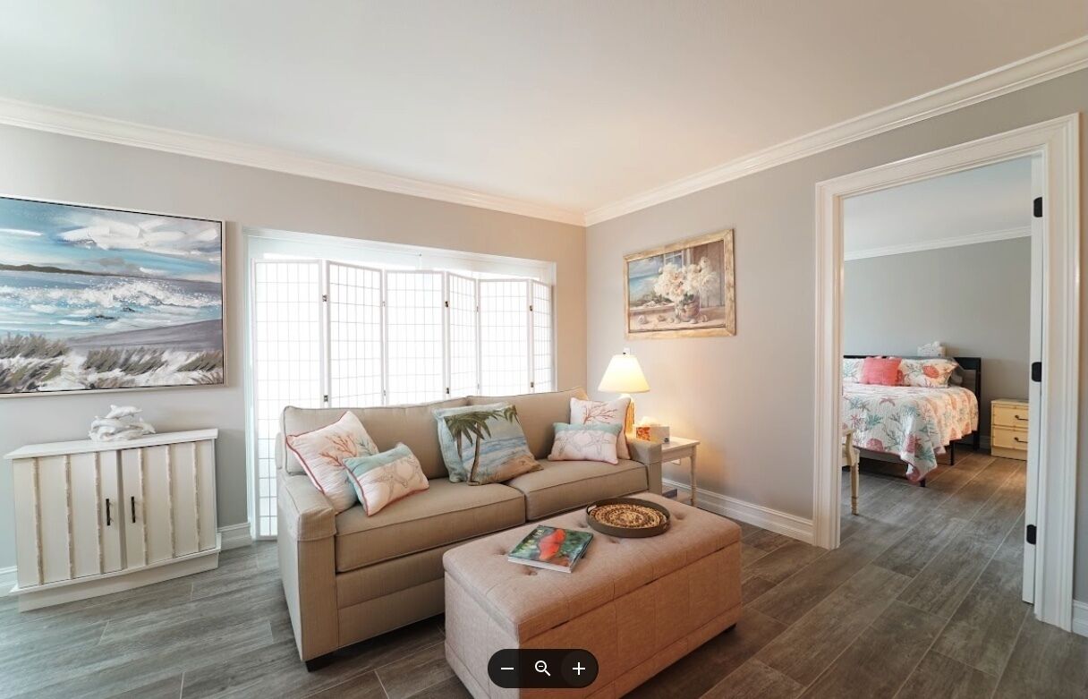 A living room with a beige sofa, a coffee table, a lamp, and a painting on the wall.