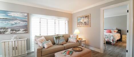 A living room with a beige sofa, a coffee table, a lamp, and a painting on the wall.