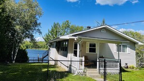 A single-story house with a porch, a small deck, and a fenced yard.