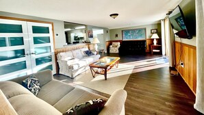 A spacious living room with a sofa, armchairs, a coffee table, and a television.