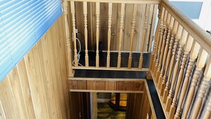 A wooden staircase with blue carpeted steps leading to a balcony.