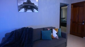 A room with a grey sofa, colorful cushions, a dark blanket, and a framed picture of the Eiffel Tower on the wall. - villa Colina Bella WITH Pool behind US EMBASSY (Santo Domingo)