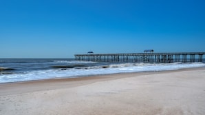Ein Strand mit einem Steg, der sich ins Meer erstreckt.