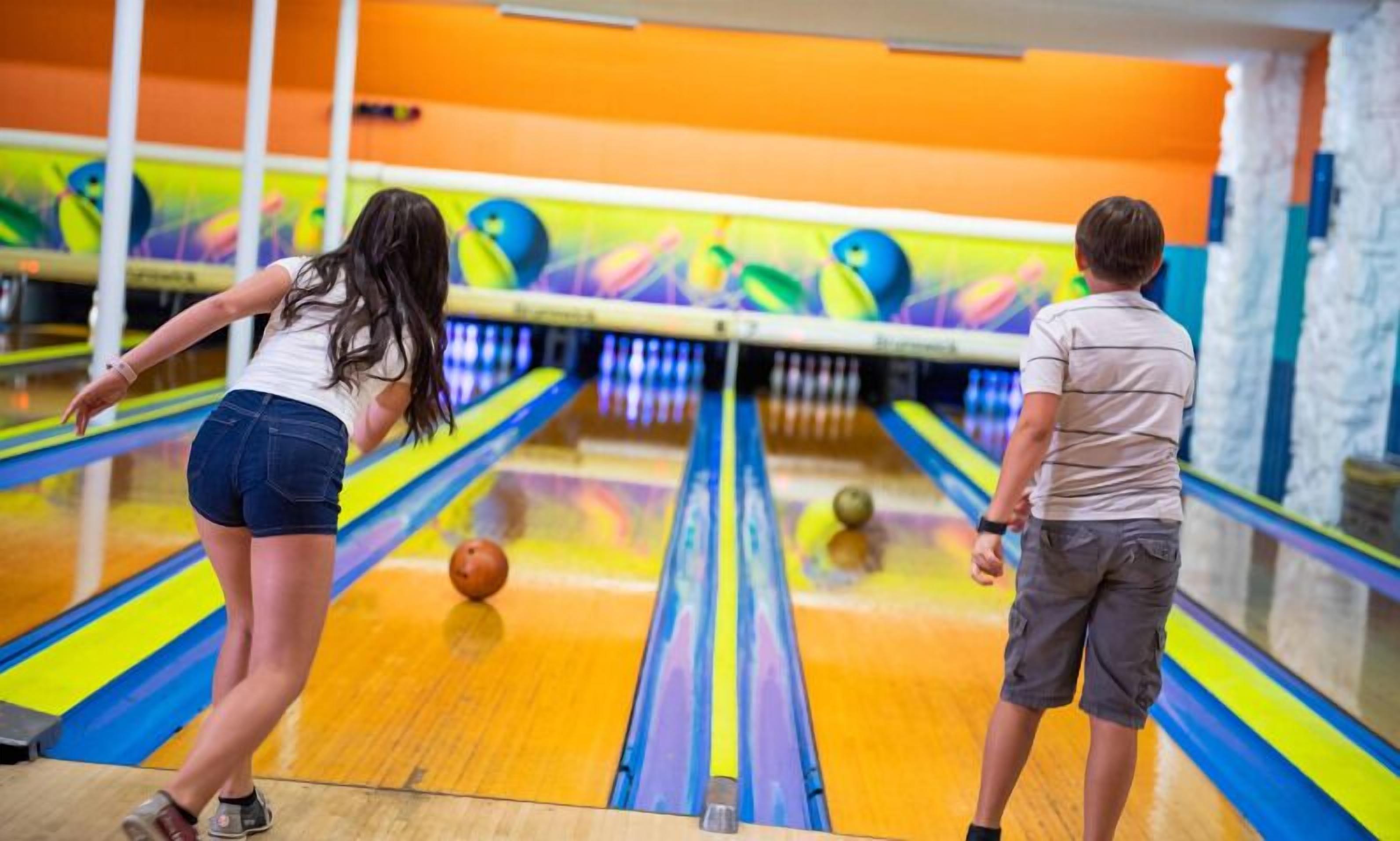 Bolera con pistas, una bola de bolos y un lanzador de bolos.