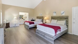 A bedroom with two beds, a mirror, bedside lamps, a dresser, and a door.
