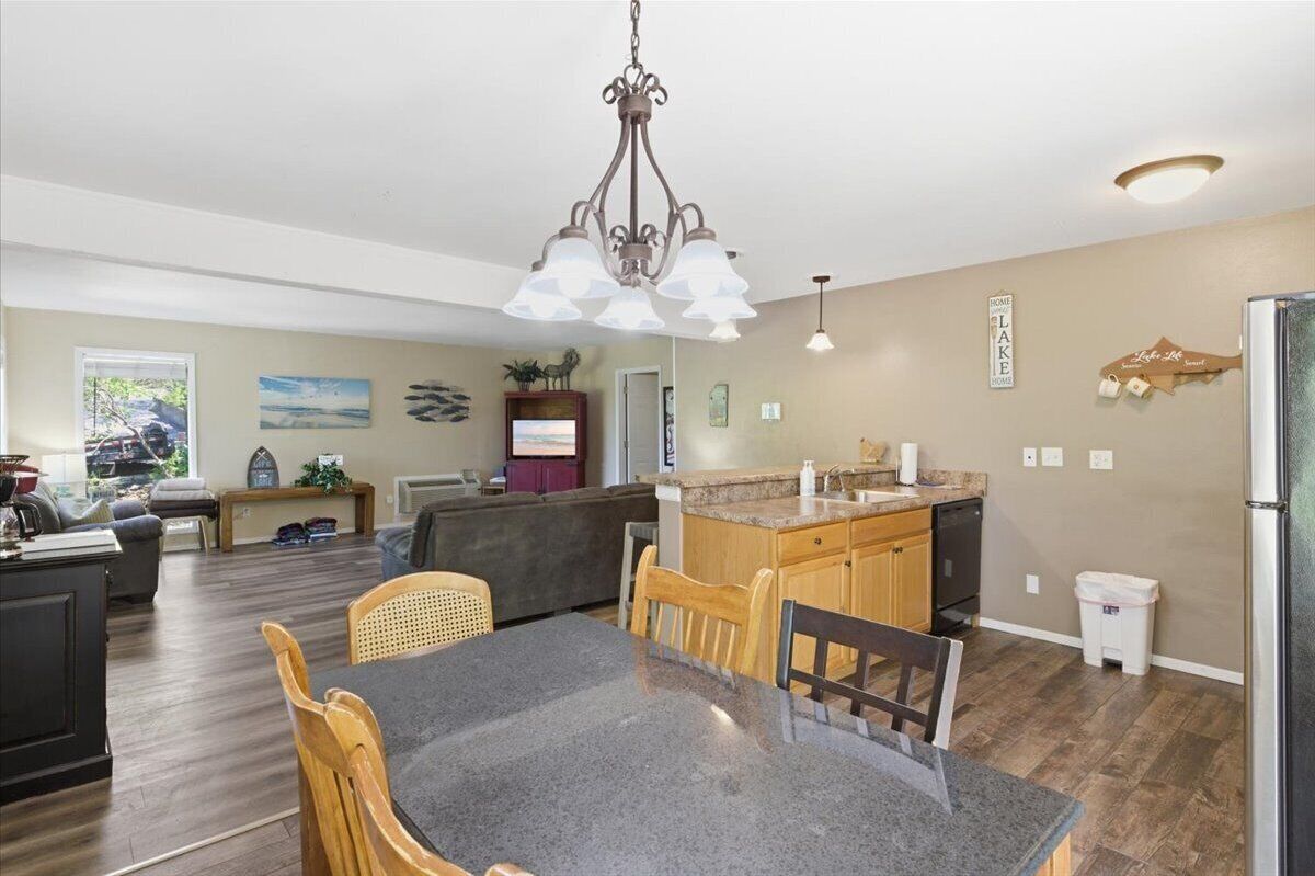 A spacious living area with a dining table, chairs, a kitchen island, and a chandelier.