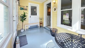 Eine Veranda mit einer Bank, einem kleinen Tisch und einem Blumentopf.