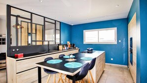 A modern kitchen with a large island, black countertops, and blue chairs. - Nice home in pont-évêque (Pont-Évêque)