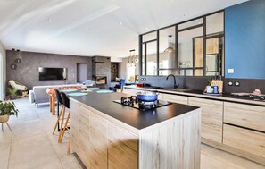 A modern kitchen with a central island, a built-in stove, and a large window. - Nice home in pont-évêque (Pont-Évêque)