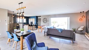 A modern living room with a sofa, chairs, a dining table, and a kitchen area. - Nice home in pont-évêque (Pont-Évêque)