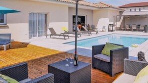 A poolside area with wicker furniture, a wooden deck, and a clear view of the pool. - Nice home in pont-évêque (Pont-Évêque)