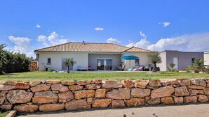 A two-story house with a tiled roof, a stone wall in the foreground, and a clear blue sky. - Nice home in pont-évêque (Pont-Évêque)