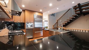 Una cocina moderna con electrodomésticos de acero inoxidable, armarios de madera y encimera negra.