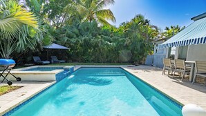 Una piscina rectangular con agua azul cristalina, rodeada por un solárium con baldosas.