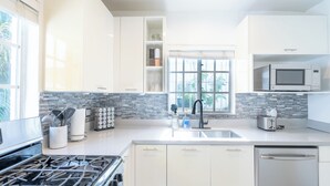 Una cocina moderna con armarios blancos, estufa a gas, lavavajillas y microondas.