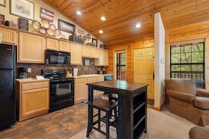 Enjoy cooking in this well-equipped kitchen with a central island, refrigerator, microwave, and stove.