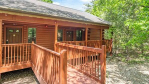 A log cabin with a porch and a covered walkway. - Romantic Studio Cabin Nestled in the Heart of Branson (Branson)