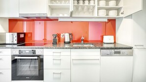 A modern kitchen with white cabinets, a granite countertop, a built-in oven, a coffee maker, a kettle, and a toaster. - Sunny St. Alban  3 Room w/ Storage, nr Train Station, by Blueground (Basel)