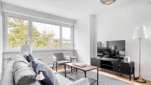 A modern living room with a grey sofa, a coffee table, a TV, and a lamp.