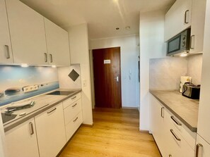 Una cocina moderna con armarios blancos, una puerta de madera y un microondas.