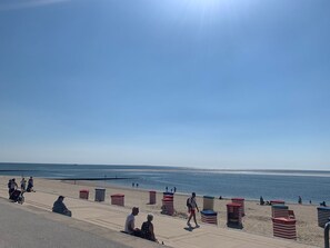 Una playa con un paseo marítimo, sombrillas y gente.