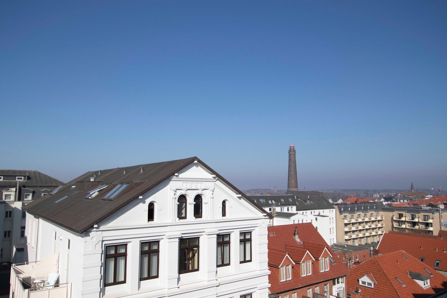 Ein weißes Gebäude mit einem Giebeldach und mehreren Fenstern.