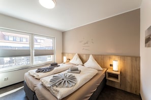 A bedroom with a bed, pillows, a bedside table with a lamp, a window, and a wall with text.